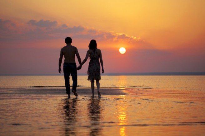 COUPLE WALKING BEACH AT SUNSET